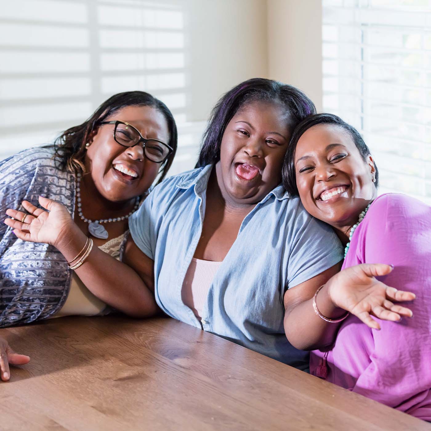 autistic girl smiling at a kitchen table with her family and friend