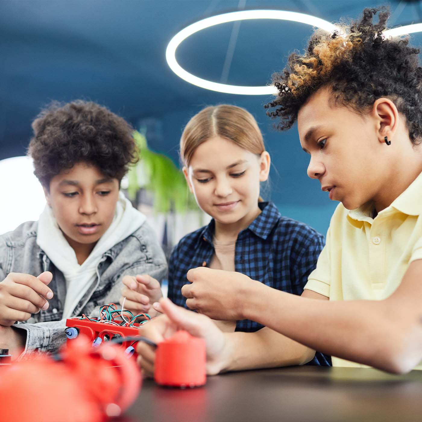 three adolescent friends working on an electrical project at school together