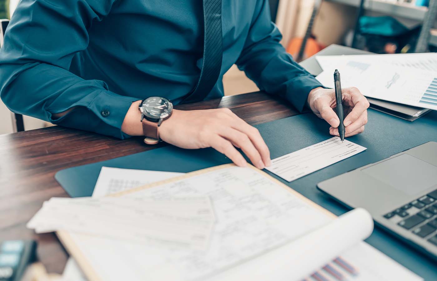 man writing a check at his desk