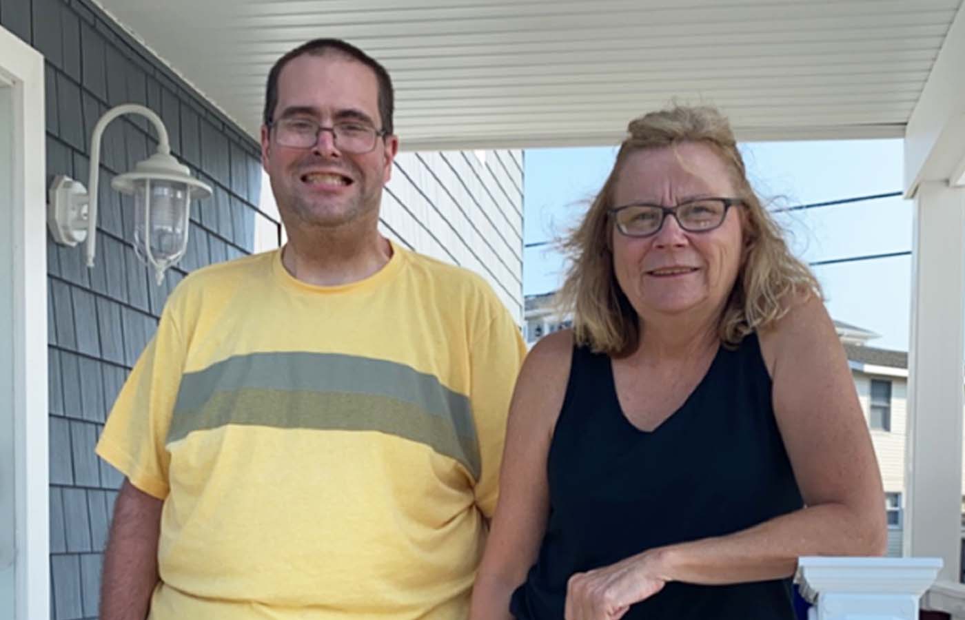 tom and maureen standing on their porch outside smiling together