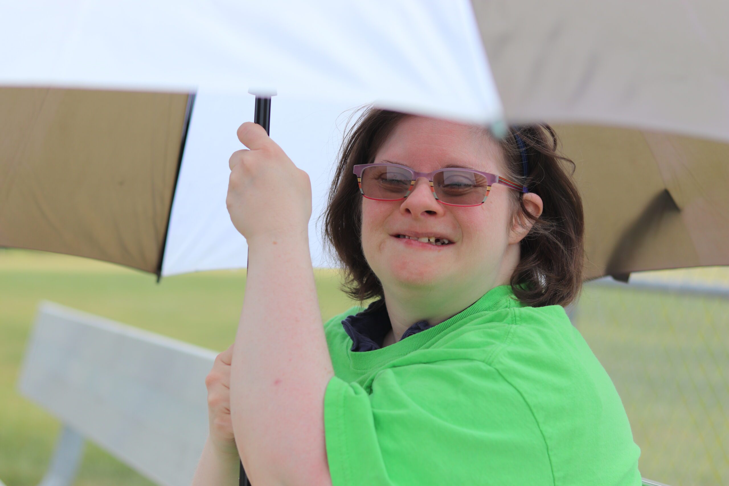 Young girl in green shirt holding an umbrella in the sun